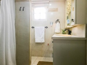 A bathroom with a shower, a sink, a mirror, and a window. - Tropical Oasis in Aruba | Walk to Palm Beach (Noord)