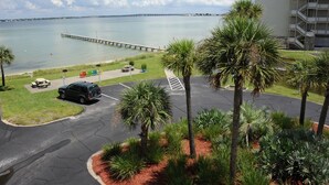 A parking lot with a view of a body of water and a pier. - Quaint Beach Condo with Bay Views, Covered Parking, Pool, Bay Beach -Baywatch C4 (Pensacola Beach)