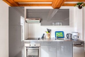 Una cuina moderna amb electrodomèstics d'acer inoxidable, un forn integrat i una cafetera.