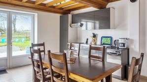 A kitchen with wooden cabinets, a stainless steel range hood, and a coffee maker. - Homerez - House Saint-Marcouf (Saint-Marcouf)