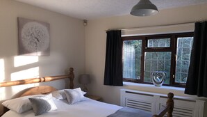 Une chambre à coucher avec un lit en bois, un radiateur, une fenêtre avec des rideaux et une lampe fixée au mur.