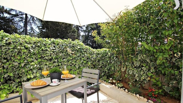 An outdoor patio with a table set for breakfast, including croissants and orange juice, under a white umbrella. - Luxury Apartments Gold and Grey (Zadar)