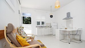 A compact living space with a kitchenette, a dining area, and a seating area with a chair and a small table. - Luxury Apartments Gold and Grey (Zadar)