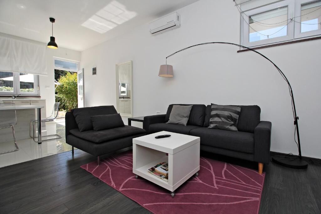 A modern living room with a dark grey sofa, a white coffee table, and a red rug.