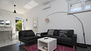 A modern living room with a dark grey sofa, a white coffee table, and a red rug. - Luxury Apartments Gold and Grey (Zadar)