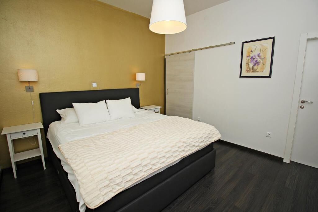 A bedroom with a bed, bedside lamps, a wardrobe, and a painting on the wall.