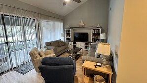 A living room with a sofa, armchairs, a coffee table, a TV, and a bookshelf. - Completely Updated Luxury Villa in Sea Pines - Beautiful Lagoon View. (Hilton Head Island)
