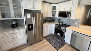 A modern kitchen with white cabinets, stainless steel appliances, a coffee maker, and a patterned rug. - Completely Updated Luxury Villa in Sea Pines - Beautiful Lagoon View. (Hilton Head Island)
