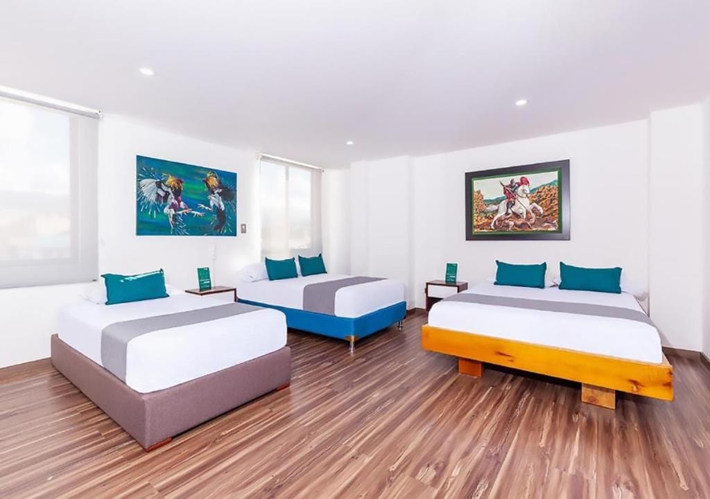 Une chambre d’hôtel avec deux lits, un plancher en bois et des œuvres d’art accrochées aux murs.