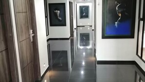 A hallway with a polished black floor, white walls, and framed artwork. - Hotel Basan Plaza (San Juan de Pasto)
