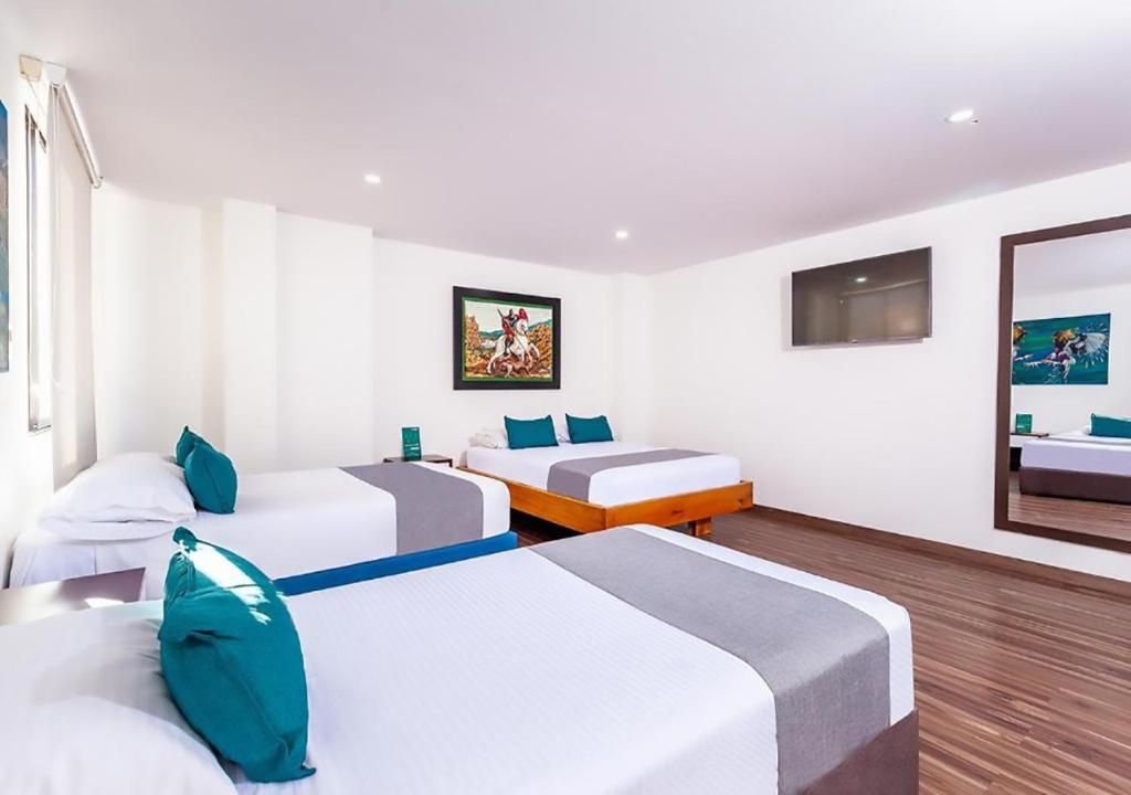 Ein Hotelzimmer mit drei Betten, einem großen Spiegel und Bildern an den Wänden.