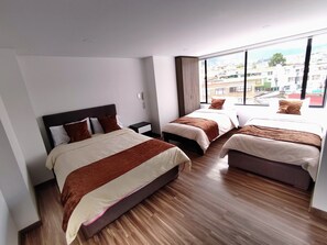 A hotel room with two beds, a large window, and a view of the city.