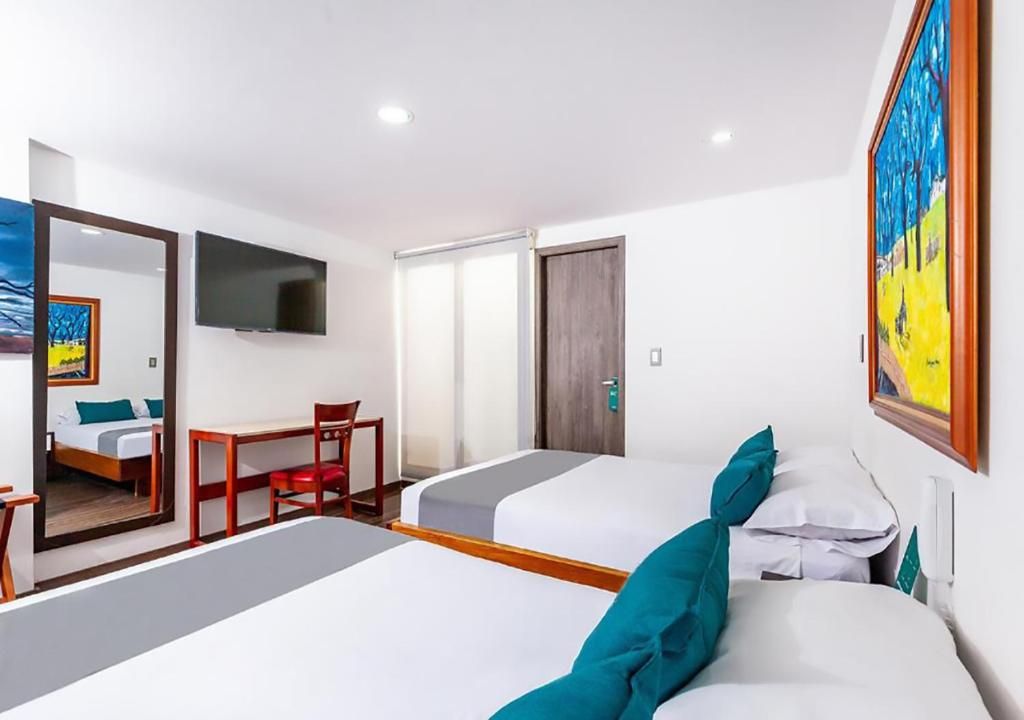 A hotel room with two beds, a desk, a chair, a television, and a door.
