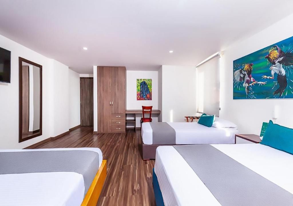 A hotel room with two beds, a desk, a chair, and a painting on the wall.