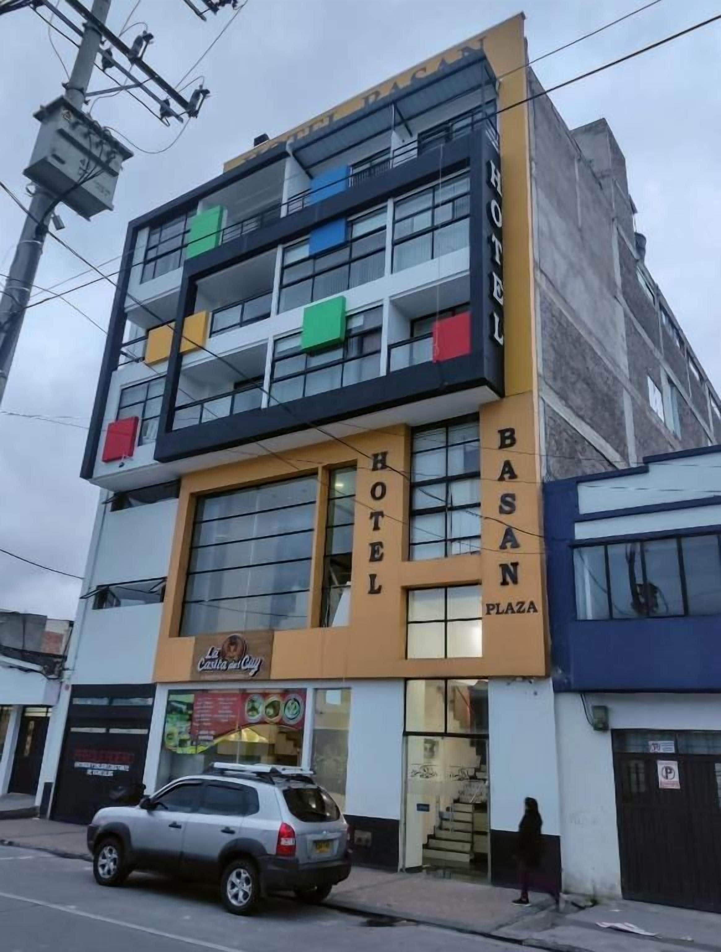 A hotel with a two-story facade, balconies, and a sign indicating it is located on Basan Plaza.