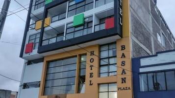 A hotel with a two-story facade, balconies, and a sign indicating it is located on Basan Plaza.