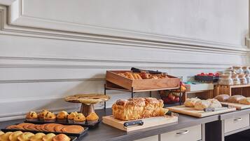 A bakery display with various baked goods and a wooden cutting board with a knife.
