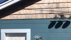 A blue building with a white door, two fish-shaped decorations, and a row of three lights above the door. - Beautiful serene cottage (Fort Bragg)
