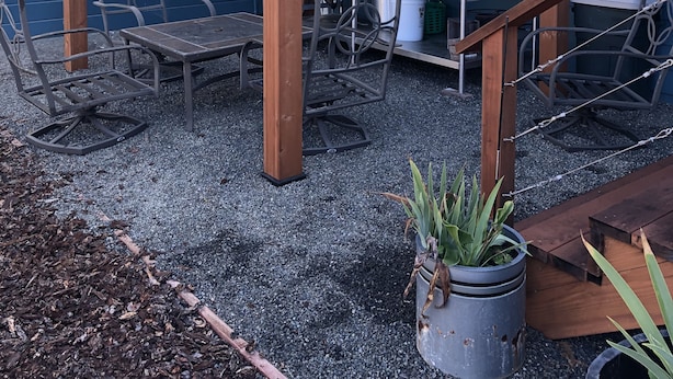 A wooden pergola with a table and chairs underneath, a hanging sign with words, and a potted plant. - Beautiful serene cottage (Fort Bragg)