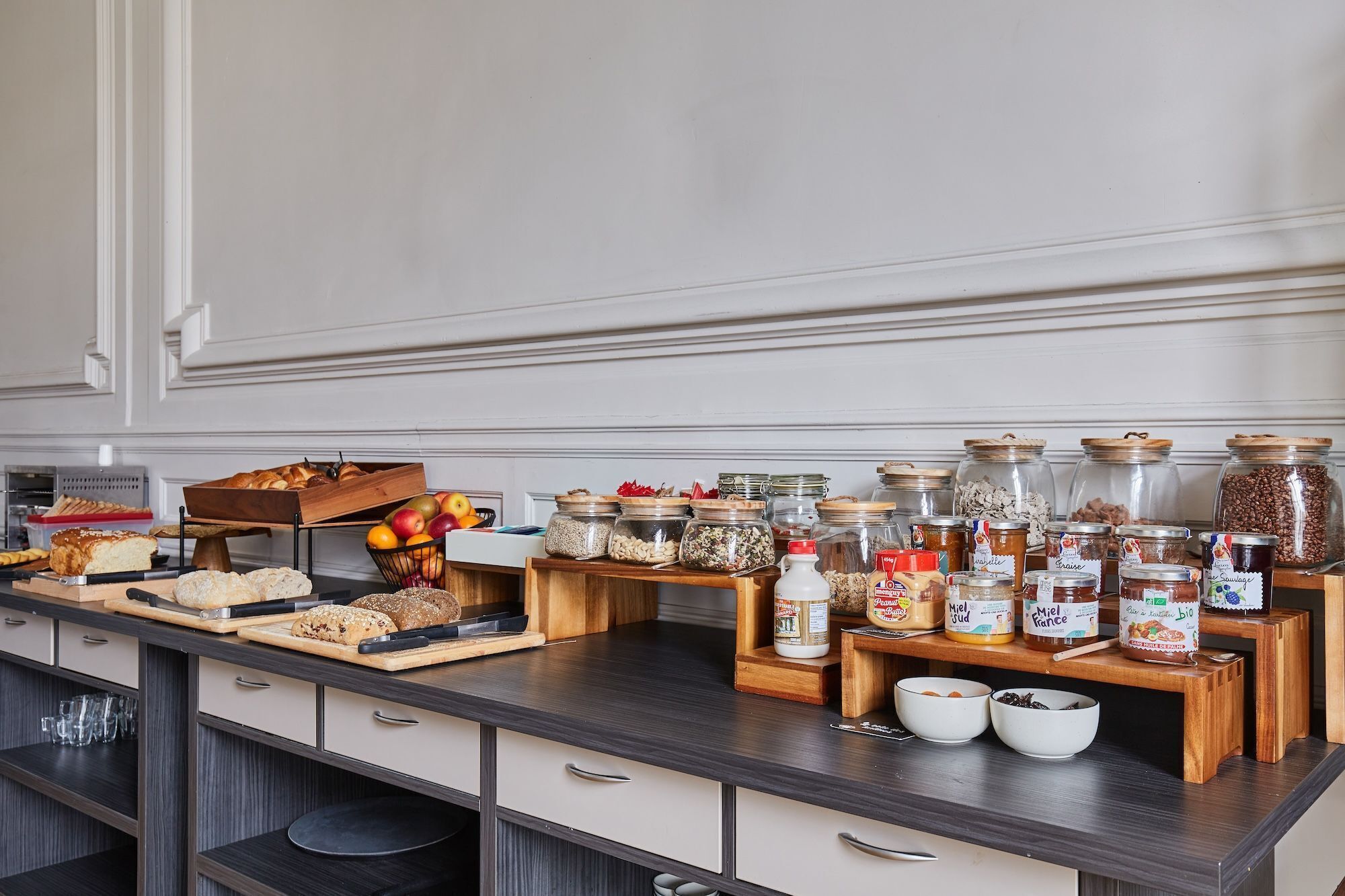 Een keukentafel met diverse etenswaren, waaronder potten jam en een presentatie van brood en gebak.