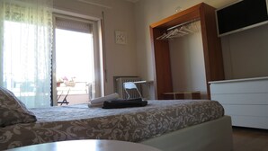 A bedroom with a bed, a chair, a radiator, and a TV. - Luna Rossa (Cagliari)
