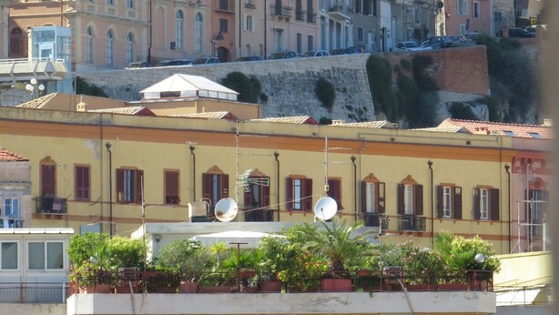 A row of multi-story buildings with balconies and satellite dishes, indicating a residential area with potential for hotel accommodations. - Luna Rossa (Cagliari)