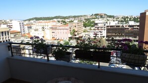 A balcony with potted plants and a view of a cityscape with buildings and a hill in the distance. - Luna Rossa (Cagliari)