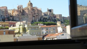 A view of a historic cityscape with a prominent building featuring a dome and a fortified wall. - Luna Rossa (Cagliari)