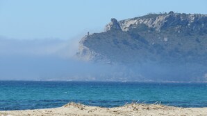 A coastal landscape with a rocky cliff and a sandy beach. - Luna Rossa (Cagliari)