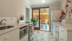 A compact kitchen with a sink, oven, and a small dining area with a chair and table.
