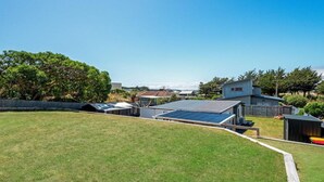 A residential property with a large lawn, a detached house, and a small shed.