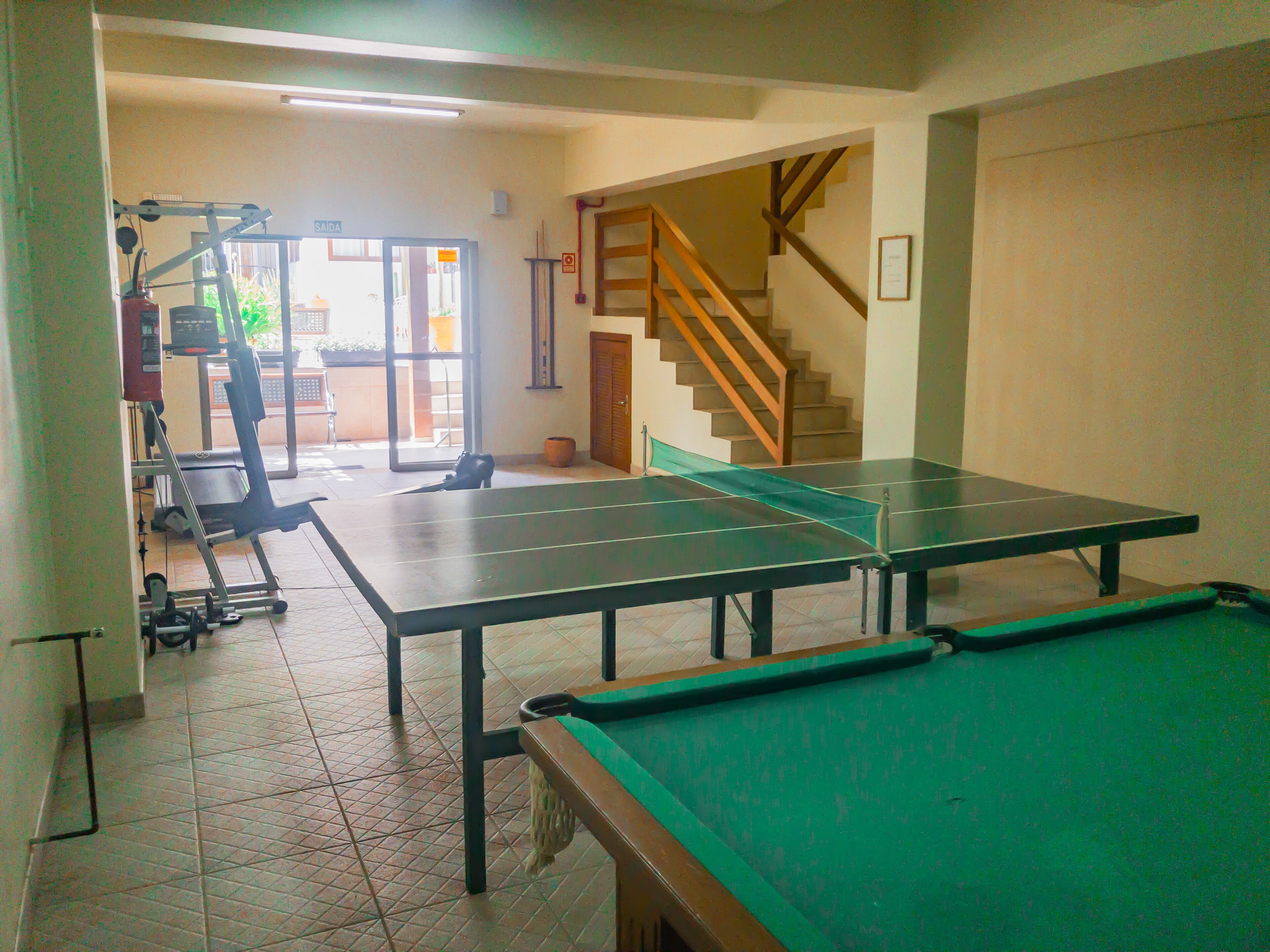 A billiards table in a room with a staircase and a door leading outside.