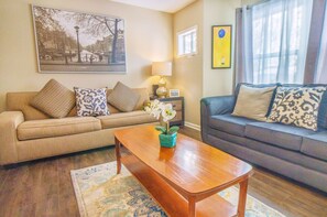 A living room with two sofas, a wooden coffee table, a rug, and a wall-mounted lamp.