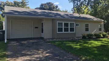 Une maison de plain-pied avec un garage, un porche à l’avant et une allée.