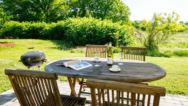 An outdoor wooden table with chairs, a bottle of wine, and a menu. - Cosy apartment for 4 people with WIFI, A/C, TV and balcony (Keszthely)
