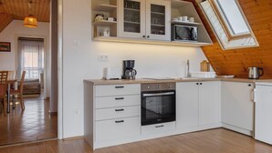 A modern kitchen with white cabinetry, a built-in oven, and a microwave. - Cosy apartment for 4 people with WIFI, A/C, TV and balcony (Keszthely)