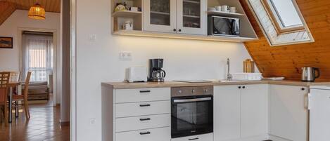 Una cocina moderna con armarios blancos, horno empotrado y microondas.