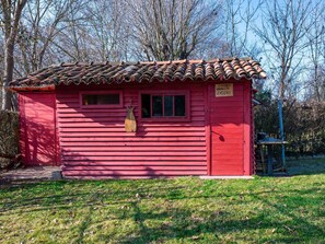Un petit bâtiment en bois rouge, avec un toit recouvert de tuiles, une fenêtre et une porte.
