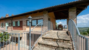 A stone staircase leading to a covered patio with a table and chairs, overlooking a scenic landscape. - Beautiful  villa for 4 people with WIFI, private pool, TV, terrace and panoramic view (Castagnole Delle Lanze)