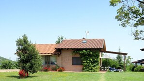 Una casa a due piani con tetto in tegole, pareti in mattoni e un portico coperto.