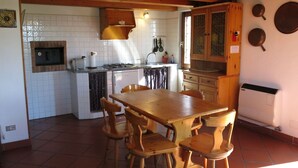 Una cucina con un tavolo e sedie di legno, un fornello e un lavello.