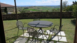 Un patio con un tavolo rotondo e quattro sedie, con vista su un paesaggio rurale suggestivo.