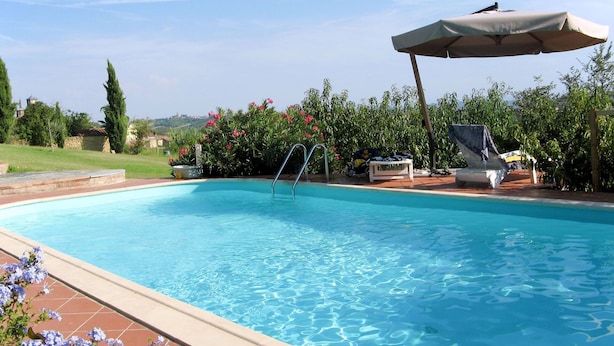 Una piscina limpida con una scala, sdraio e un ombrellone.