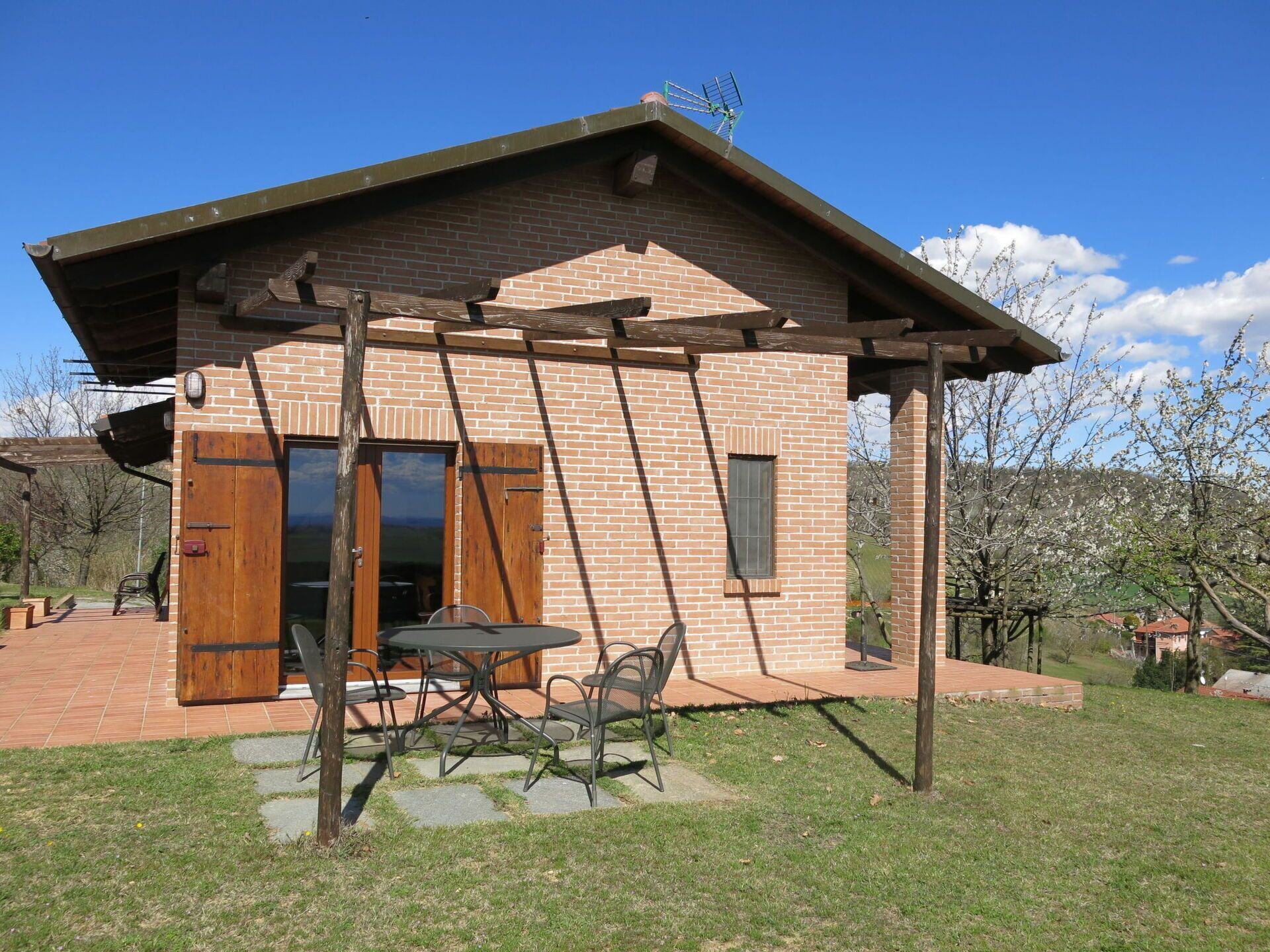 Une maison en briques avec une véranda en bois, une table et des chaises à l’extérieur.