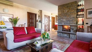 A cozy living room with a stone fireplace, a sofa, and a coffee table. - Wonderful  villa for 8 guests with private pool, A/C, WIFI, hot tub, TV and terrace (Narzole)