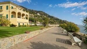 A paved walkway with benches, a yellow building with arches, and a hillside in the background. - Lovely apartment for 4 guests with A/C, pool, WIFI, TV, terrace and pets allowed (Ventimiglia)