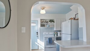 A modern kitchen with white cabinetry, a central island, and a hanging light fixture. - The Comfy Craftsman l KING Beds l Near Park l Spacious Home (Spokane)