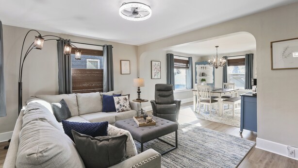 A modern living room with a sofa, ottoman, and a dining area in the background. - The Comfy Craftsman l KING Beds l Near Park l Spacious Home (Spokane)
