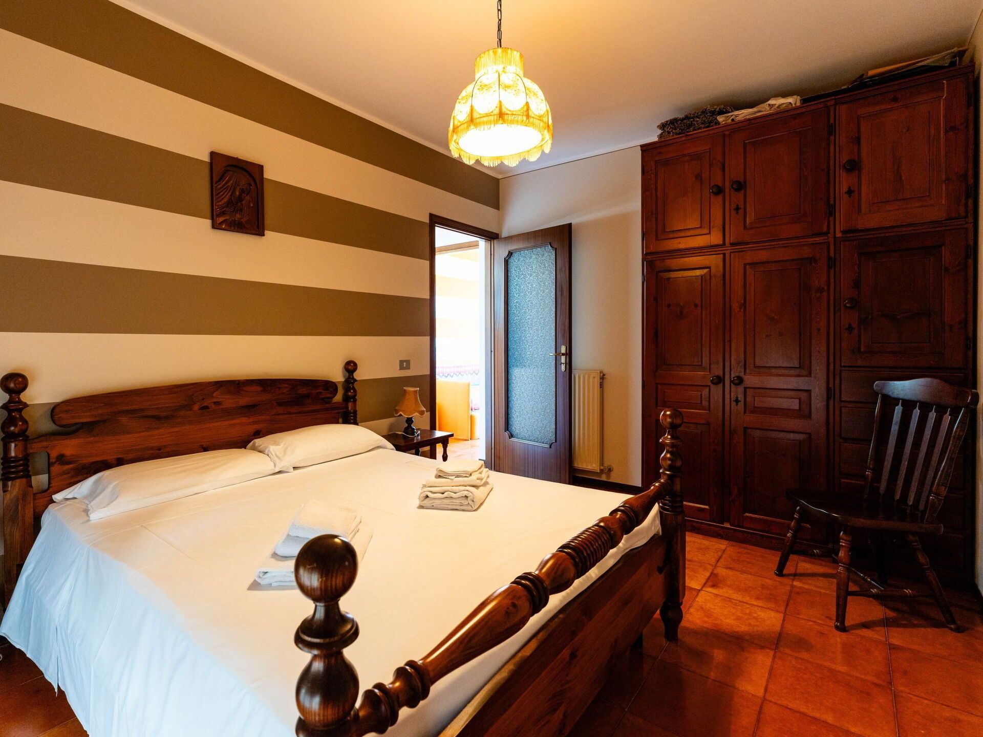 Ein Hotelzimmer mit einem großen Bett, einem Holzschrank und einer Pendelleuchte.