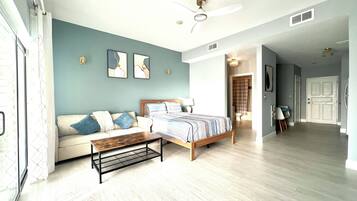 A bedroom with a bed, a sofa, a coffee table, and a ceiling fan.